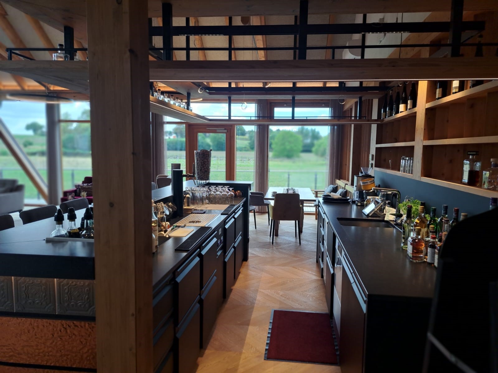 Bar mit schwarzer Theke, Holzdetails und Spirituosenflaschen, geplant von Heiser's Küchen.