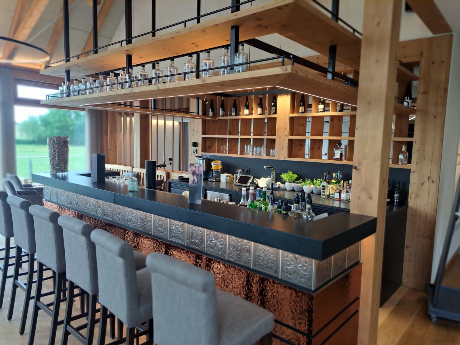 Moderne Bar von Heiser's Küchen mit schwarzer Front, Holzakzenten und dekorativen Spirituosenflaschen.