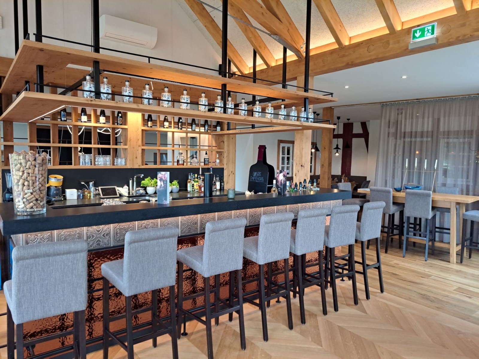 Elegante Bar von Heiser's Küchen mit schwarzer Front, Holzakzenten, Spirituosenflaschen und einer Theke mit Barhockern.